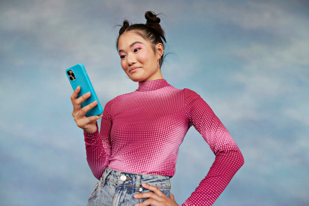 teenage girl using mobile phone while standing against colored background